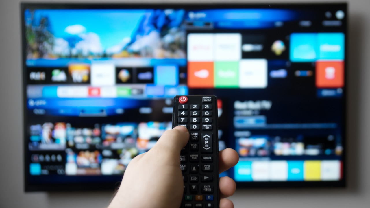 Hand mit Fernbedienung vor einem Smart-TV