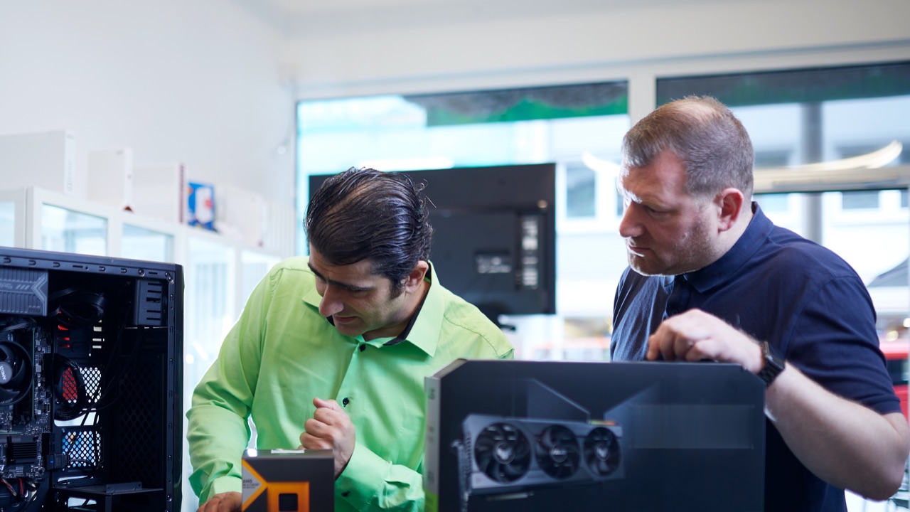 Frank Samirae, Inhaber, und ein Kunde beugen sich über einen geöffneten PC