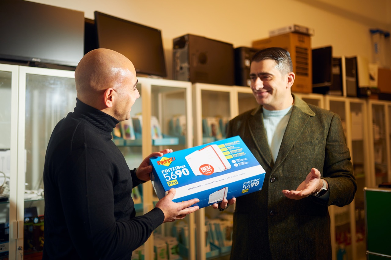 Frank Samirae, Inhaber, übergibt einem Kunden eine FRITZ!Box